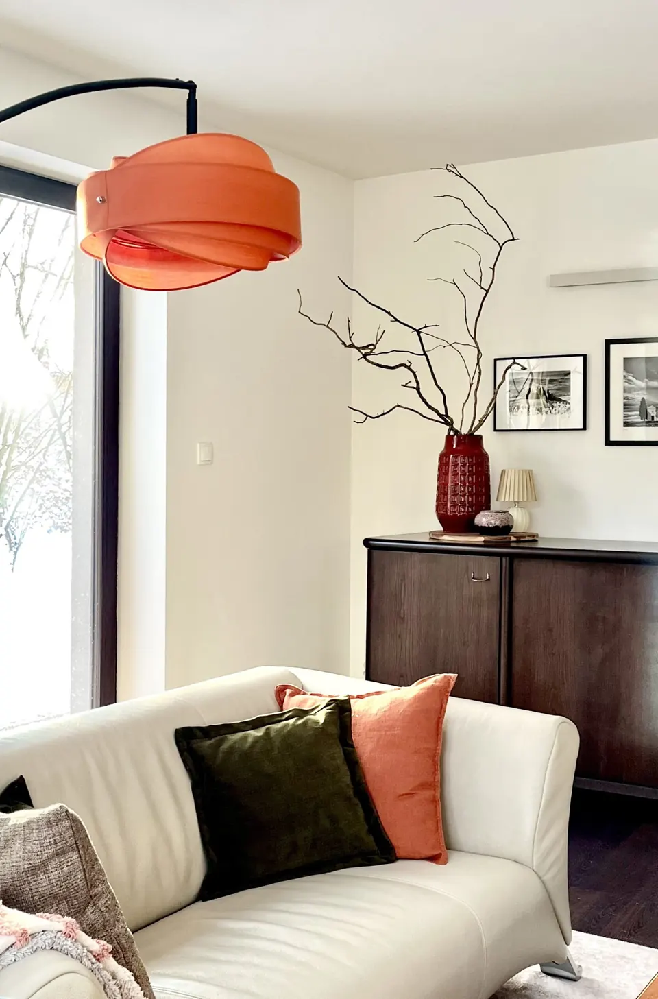 Stylizowany salon – komoda, czerwony wazon z gałązkami i pomarańczowa lampa