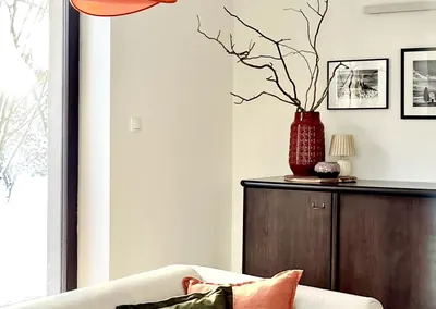 Stylizowany salon – komoda, czerwony wazon i pomarańczowa lampa